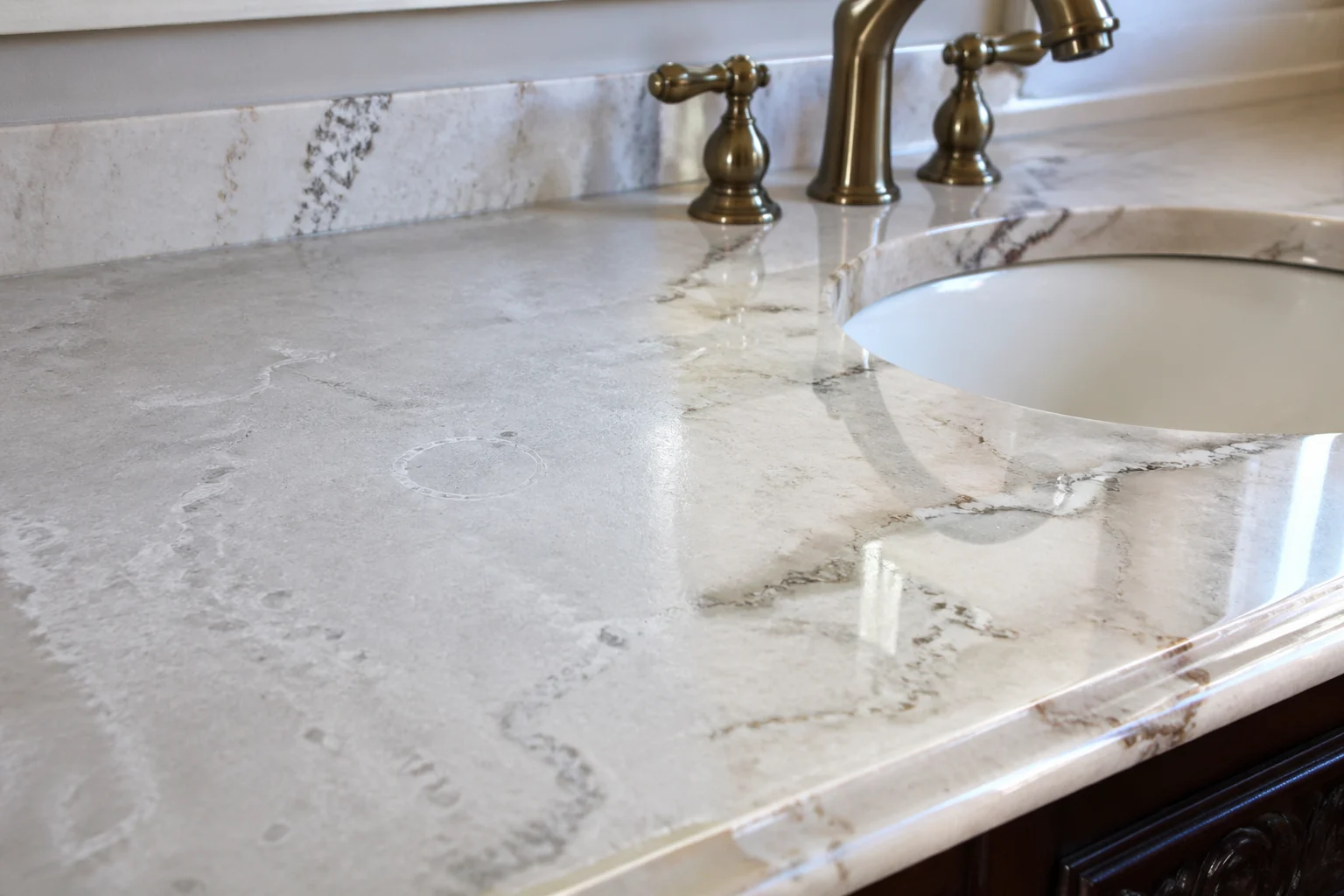 Dull stone countertop with hard water rings near a faucet before polishing